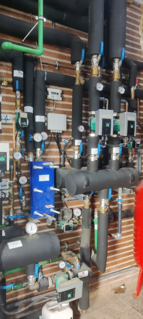 Sala de máquinas de la instalación de climatización del Centro de Salud de Bembibre con colectores hidráulicos, grupos de bombeo e intercambiador de placas.